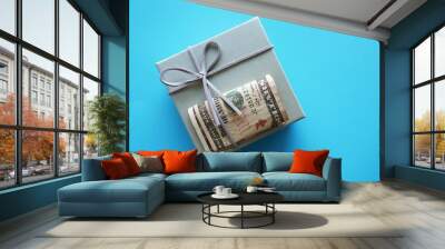 Grey gift box with cash dollars money on blue copy space background, concept of money gift giveaway or bonus to employees at year-end Christmas Holiday season Wall mural