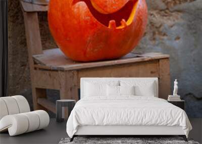 Close-up carved pumpkin on the old chair used for decoration of street on the Halloween holiday Wall mural