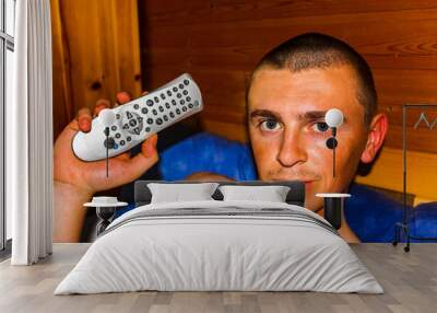 Man in wooden house on couch with remote control in Germany. Wall mural