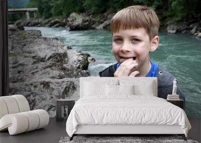 Child eating biscuit on bank of Belaya river in granite gorge Wall mural