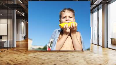 Child eating boiled corn on beach Wall mural