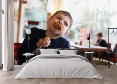 Kid eating cutlet in restaurant Wall mural