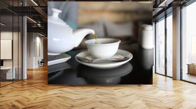 Person pours tea from white teapot Wall mural