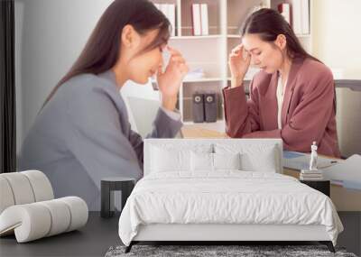 Asian woman pressing 2 hands on forehead feeling stressed, worried about bad financial business with documents and laptop on table Wall mural