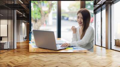 Asian woman sitting at desk with graph document and laptop computer at business woman in office looking at financial statistics graph. data analysis Profit Growth Business Ideas Wall mural