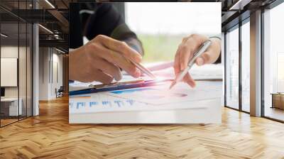 Business team discussing and planning projects using charts, holding pens and analytical papers on office table. with a laptop computer and a financial graph running in the background. business idea Wall mural