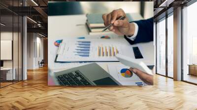 Close up of businessman hand holding pen and pointing at financial documents and investment plan for business and stocks and graph chart for investment analysis in his office Wall mural