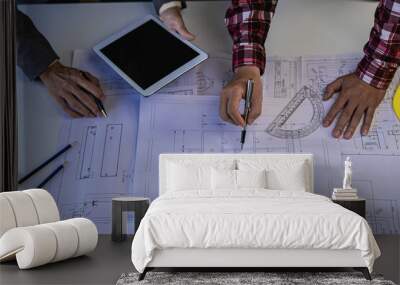 Engineer pointing at blueprint and using laptop to draw building design project in office construction concept
and meeting structure engineers or architects collaborating with partners. Wall mural