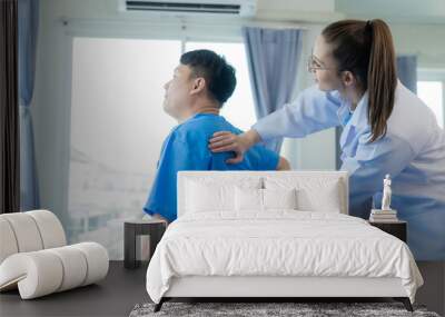 Female doctor doing physiotherapy stretching male patient's shoulder, doctor doing osteoporosis treatment exercise in modern clinic. Wall mural