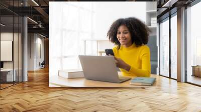 Happy young woman using laptop sitting at desk writing notes while watching webinar. Study online. Look at web learning or have online meeting, distance learning concept. Wall mural