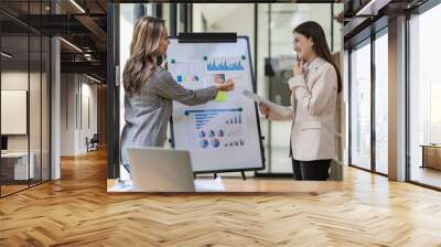 Two asian businesswoman sitting and consulting business inside modern office discussing presentation of startup project idea Analyze statistics and investment markets at the office. Wall mural