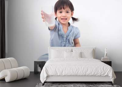 Asian little cute girl 4 years old holding empty glass after drink all the milk  on white background. Milks is essential and nutrition for the child's body. Wall mural