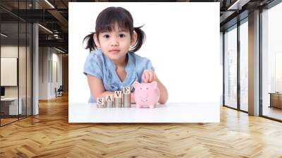 Asian little cute girl 4 years old saving money in to a pink pig isolated on white background. Wall mural