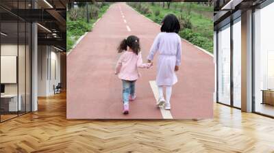 Brunette Latina 4 and 5 year old girls walk holding hands like sisters and friends spending time together outdoors Wall mural