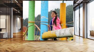 Latin little girl with long straight black hair, overweight body positive and does sports playing in the playground in the middle of the forest and mountains with trees
 Wall mural