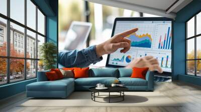 A person points at detailed graphs and charts displayed on a laptop screen, showcasing analytical skills and data interpretation essential for modern business decision-making. Wall mural