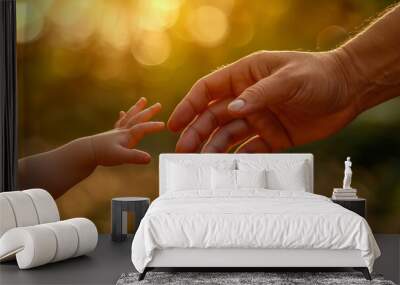 Close-up of an adult hand reaching out to a child's hand with golden light Wall mural