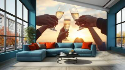 Multiple hands clink champagne glasses aloft in a celebratory toast at sunset, capturing a festive moment. Wall mural