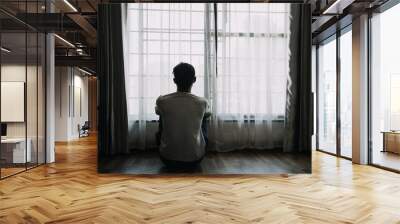 Alone man silhouette staring at the window closed with curtains in bedroom. Man stands at window alone Wall mural