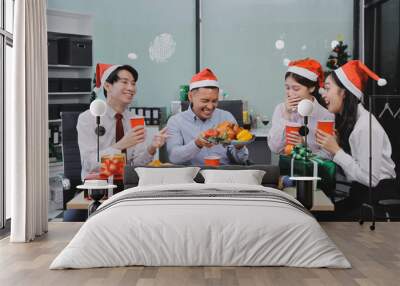 full length view of a group of business team wearing red Santa hat and exchange gift box together in the office for Christmas. Wall mural