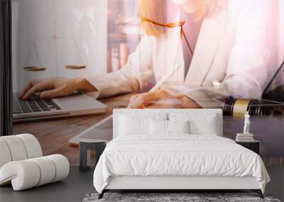 Justice and law concept.Male judge in a courtroom with the gavel, working with, computer and docking keyboard, eyeglasses, on table in morning light Wall mural