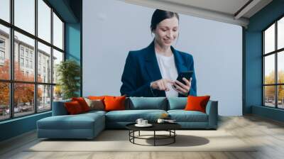 Portrait of a happy asian businesswoman using mobile phone isolated over white background Wall mural