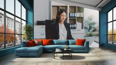 Portrait of Young Asian woman hand freelancer is working her job on computer tablet in modern office. Doing accounting analysis report real estate investment data, Financial and tax systems concept. Wall mural