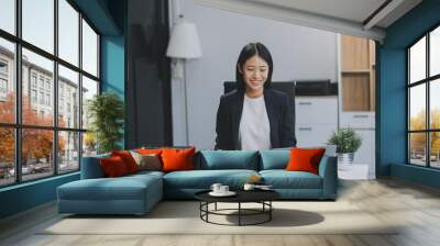 Portrait of Young Asian woman hand freelancer is working her job on computer tablet in modern office. Doing accounting analysis report real estate investment data, Financial and tax systems concept. Wall mural