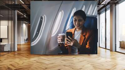 Traveling and technology. Flying at first class. Pretty young businees woman using smartphone while sitting in airplane. Wall mural