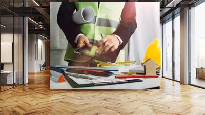 Two colleagues discussing data working and tablet, laptop with on on architectural project at construction site at desk in office Wall mural