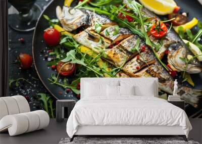 Closeup of a delicious grilled fish dish with lemon, tomatoes, and arugula on a black plate. Wall mural