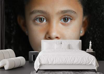 Close up of afro little girl sad looking at camera with brown eyes and curly hair Wall mural