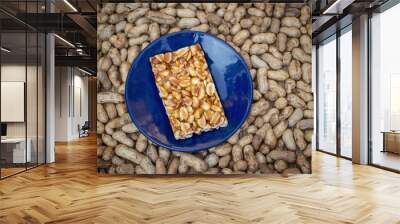 Peanut Chikki or Jaggery Peanut Brittle Sweets in a Blue Plate Isolated on Peanut Pods Wall mural