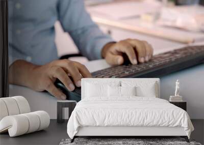 Closeup of Indian businessman typing on keyboard and scrolling mouse at desk in office Wall mural