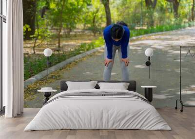 Tired young woman taking rest after doing physical exercise outdoors, fitness concept Wall mural