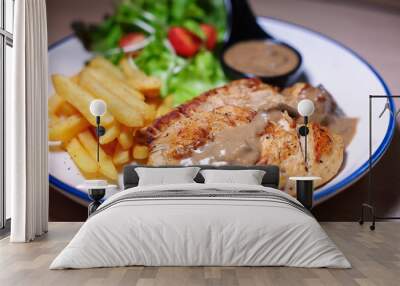 Chicken steak with side dishes of French fries, salad and pepper sauce on a white plate, photographed with studio lights. Wall mural