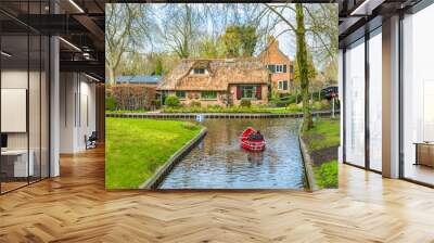 Canal intersection, a boat in and houses on the e waterfront in Giethoorn, Netherlands Wall mural