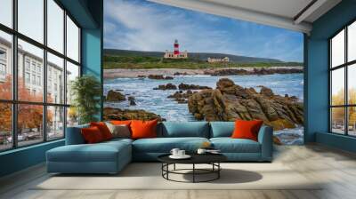 Cape Agulhas Lighthouse, southernmost tip of Africa from the ocean with rocks and blue water, L'Agulhas, South Africa Wall mural