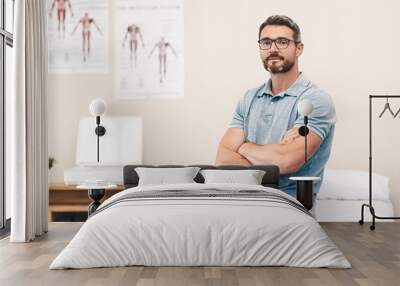 Helping you heal is my job. Portrait of a handsome mature male physiotherapist posing with his arms folded in his office. Wall mural