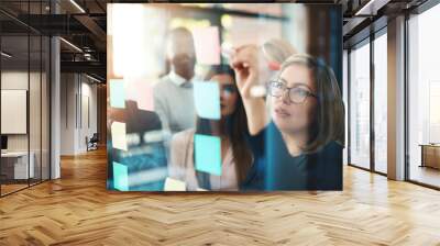 Marketing leader planning and writing on sticky notes on wall while support and sharing vision or idea. Diverse group of creative office business people meeting together to market new startup company Wall mural