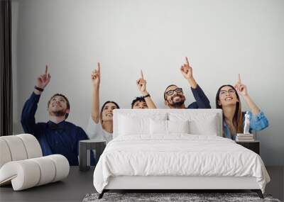 No matter how far it seems, go after your dream. Shot of a group of young people pointing towards something above them inside. Wall mural