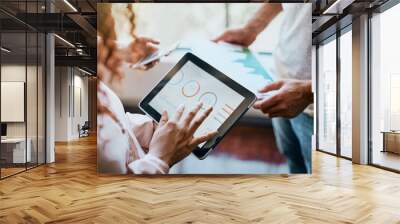 The calculations have been made. Shot of two unrecognizable peoples hands working on a tablet and looking at the businesss charts in the office. Wall mural