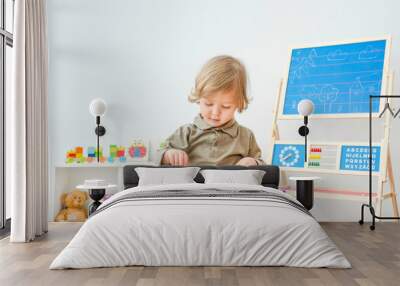 Cute little child having fun at home playing with colorful stamps on paper. Indoor activity for kids. Wall mural