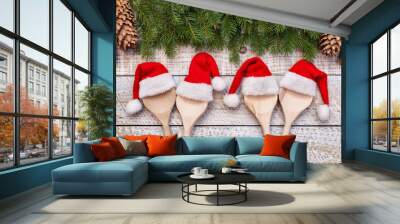 Christmas party food concept with wooden spoons wearing santa hats on white table Wall mural