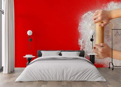 Young hands with rolling pin and flour on red table - large copy space Wall mural