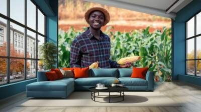 African farmer man holding a fresh corn at organic farm with smile and happy.Agriculture or cultivation concept Wall mural