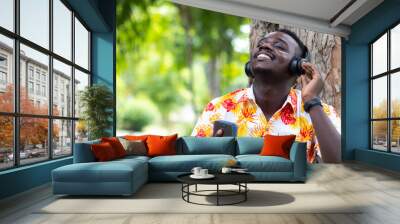 African man listening to music from smartphone with bluetooth or wireless earphones with smile and happy.16:9 style Wall mural