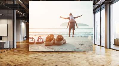 Rubber slippers on the beach with freedom father and daughter standing and watching the sunrise Wall mural