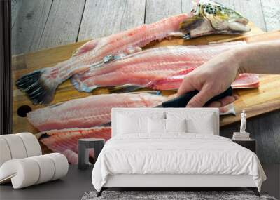 Filleting trout , removing rib bones with sharp fillet knife on wooden board Wall mural