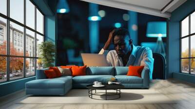 African american businessman working late at night in office. African-american entrepreneur in formal wear sitting at desk and working late at night . Wall mural